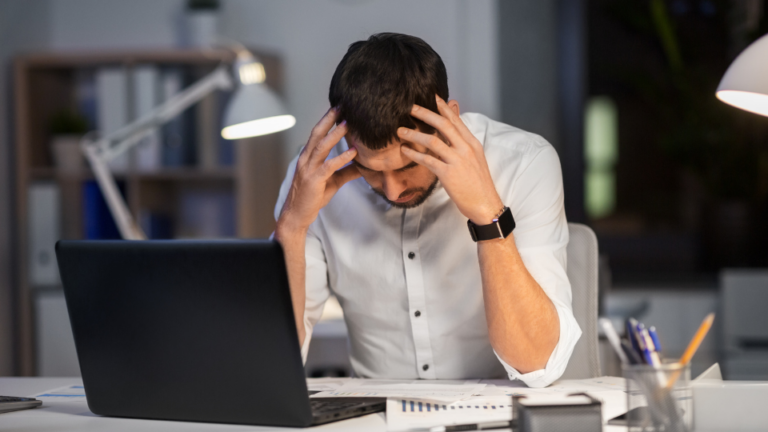 Homme stressé assis à son bureau devant un ordinateur